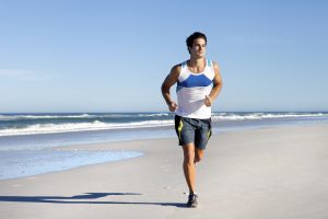 Imagem de um homem correndo na praia com tênis.