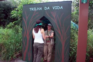 Fotografia de uma pessoa entrando na trilha da vida sendo guiada pelo instrutor.