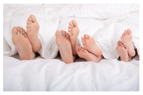 Fotografia dos pés de três pessoas na cama.