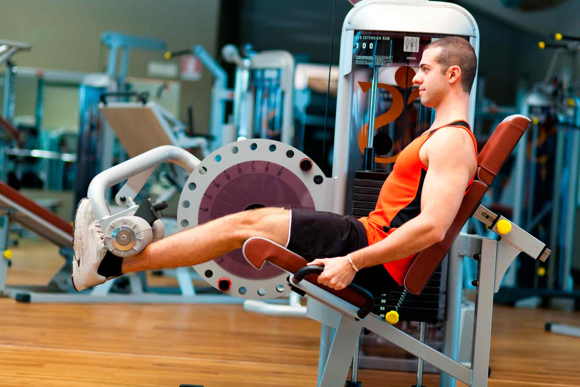 Homem jovem em uma cadeira flexora de academia