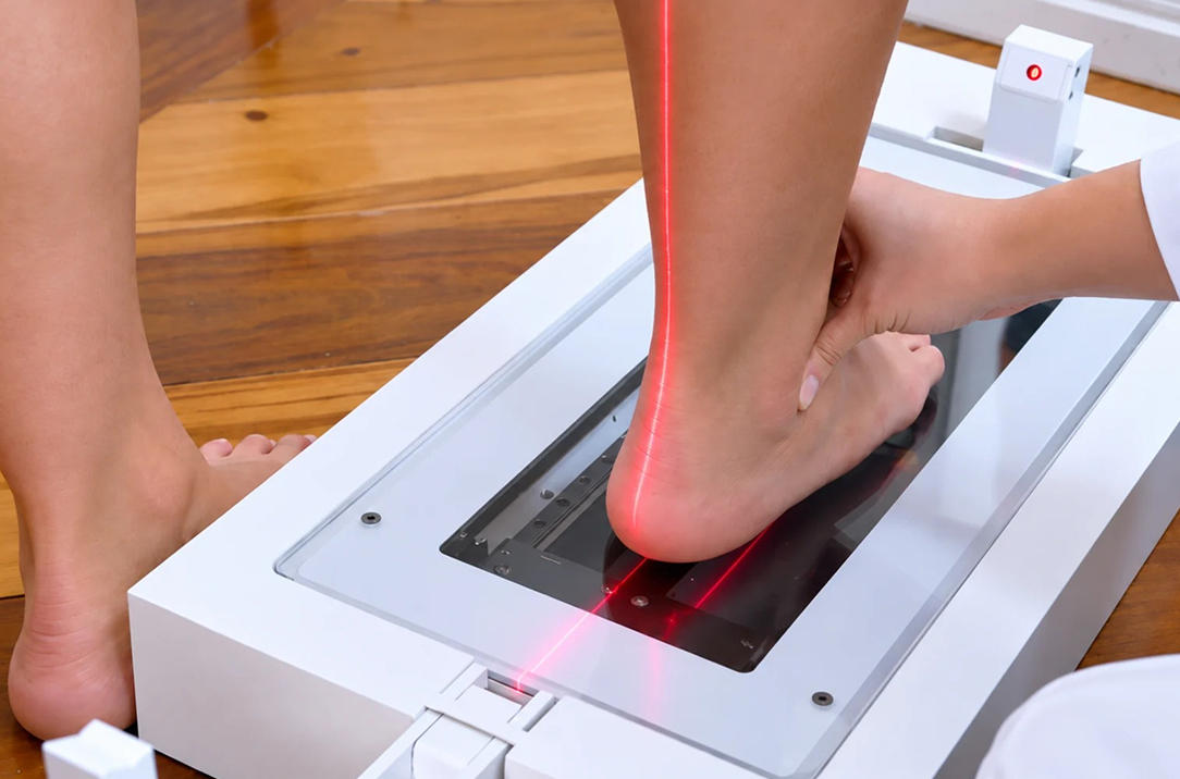Especialista posicionando o pé de um cliente no escâner 3D com a linha de laser vermelha